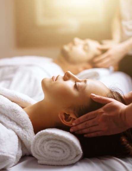 A woman and man both looking relaxed and receiving a head massage